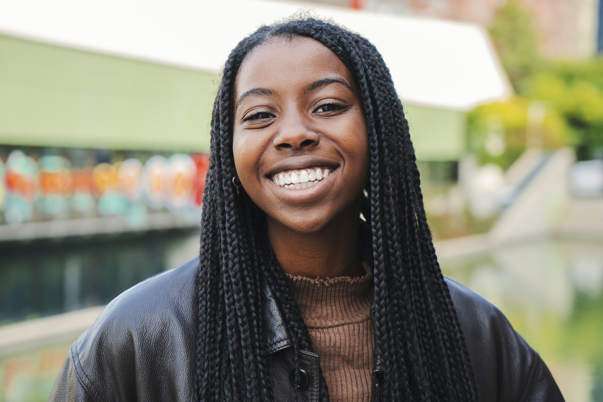 Young african american woman with braids smiling and laughing looking at camera. Front view of one